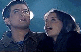 a man and a woman are standing next to each other and looking up at the sky .