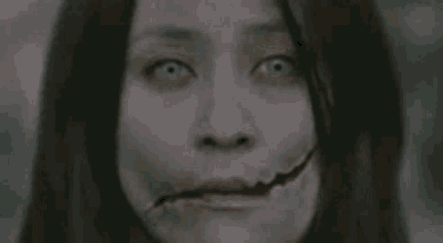 a close up of a woman 's face with a broken mouth and green eyes .