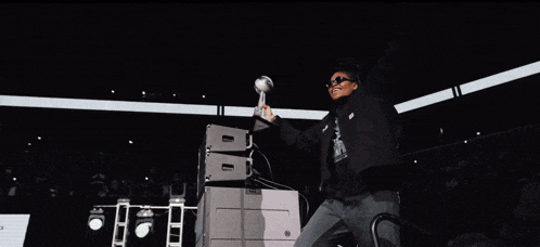 a man in a black jacket is holding a trophy in the air