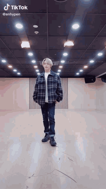 a man is standing in a room with a wooden floor and a black ceiling .