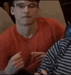 a man wearing glasses is sitting on a couch with his eyes closed .