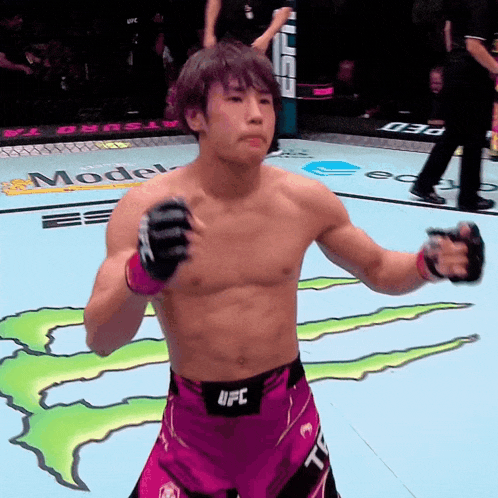a fighter wearing a belt that says ufc stands in front of a monster energy logo