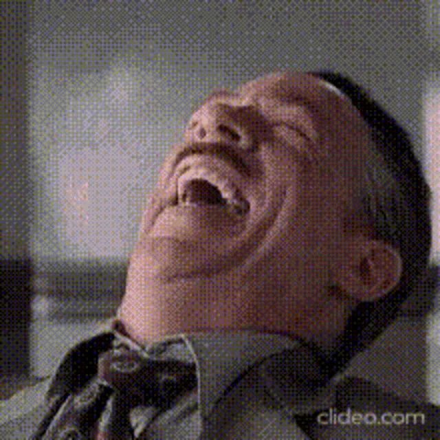 a man in a tie is laughing with his mouth open