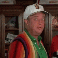 a man wearing a white hat and a rainbow sweater is standing in front of a locker .