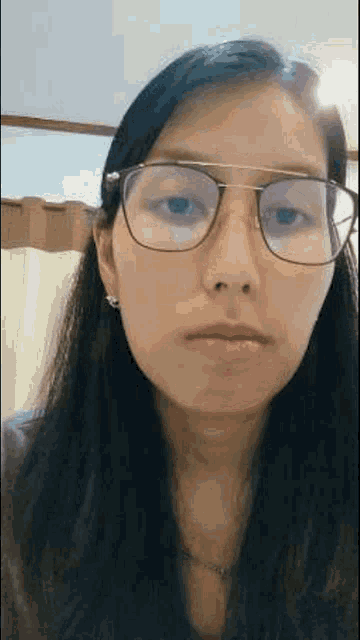 a woman wearing glasses is looking at the camera and making a funny face .