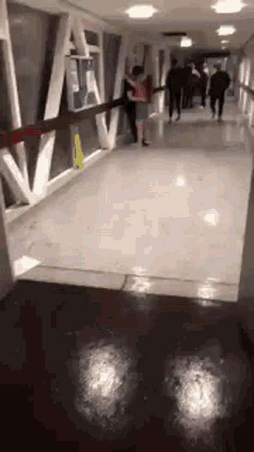 a woman is walking down a hallway with a man holding her .