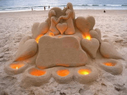 a sand sculpture of a man and a woman holding hands on a beach .