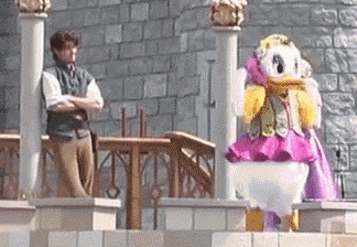 a man is standing next to a statue of daisy duck in a pink dress .
