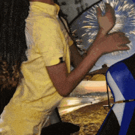 a person in a yellow shirt is playing with a blue and white object