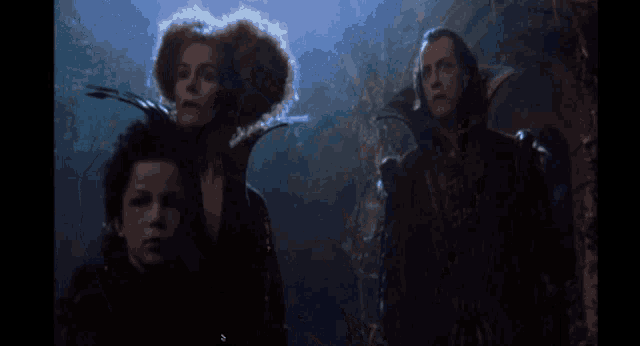a group of people are standing in a dark room and one of them is wearing a feathered collar