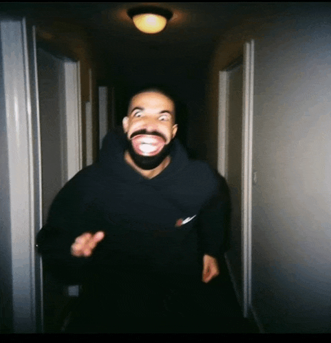 a man with a beard is making a funny face in a dark hallway .