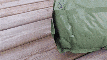 a green bag on a wooden surface has the number 133 on it