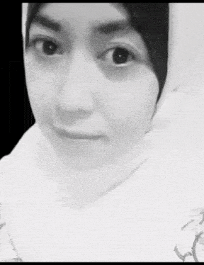 a black and white photo of a woman wearing a hijab and a white shirt .