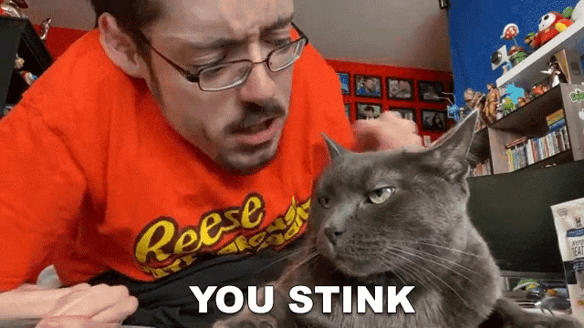 a man in an orange reese 's t-shirt is petting a cat
