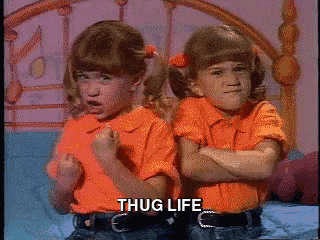 two little girls are sitting on a bed with their arms crossed and the word thug life is on the bottom