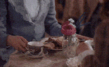 a woman is sitting at a table holding a cup of coffee .