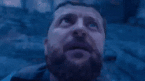 a man with a beard is looking up into the sky in a dark room .