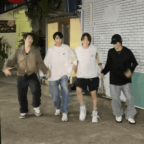 four young men are dancing in front of a pizza shop