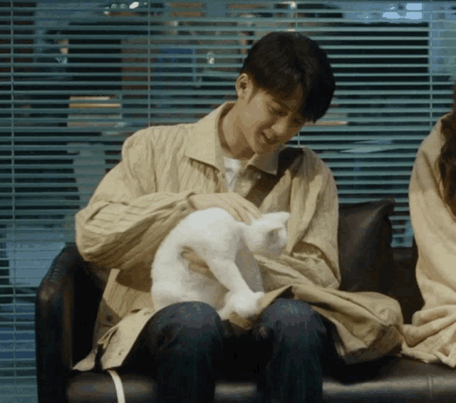 a man is petting a white cat on a couch