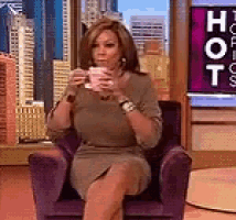 a woman is sitting in a chair drinking from a cup .