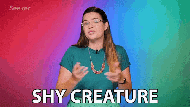 a woman with glasses and a necklace is saying " shy creature "