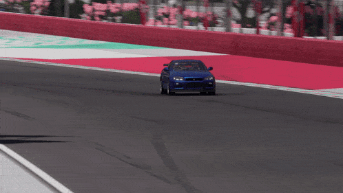 a blue car is driving down a race track with a green and white stripe