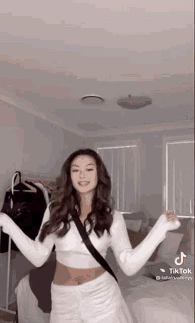 a woman is dancing in a bedroom with her arms outstretched .