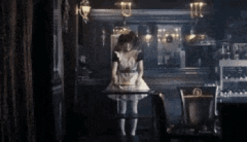 a woman in a maid costume stands in a dark room