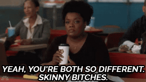 a woman is sitting in a diner holding a cup of coffee and says yeah you 're both so different skinny bitches