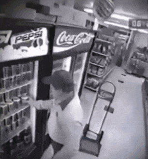 a man is reaching into a coca cola fridge in a store