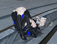 a man and a woman are sitting on a sidewalk with the woman laying on the man 's lap