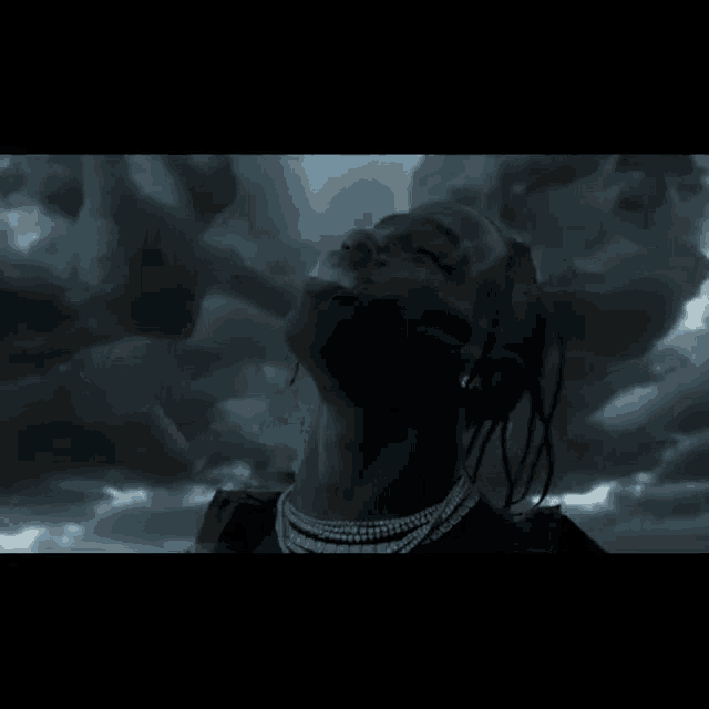 a man with dreadlocks is smoking a cigarette with smoke coming out of his mouth