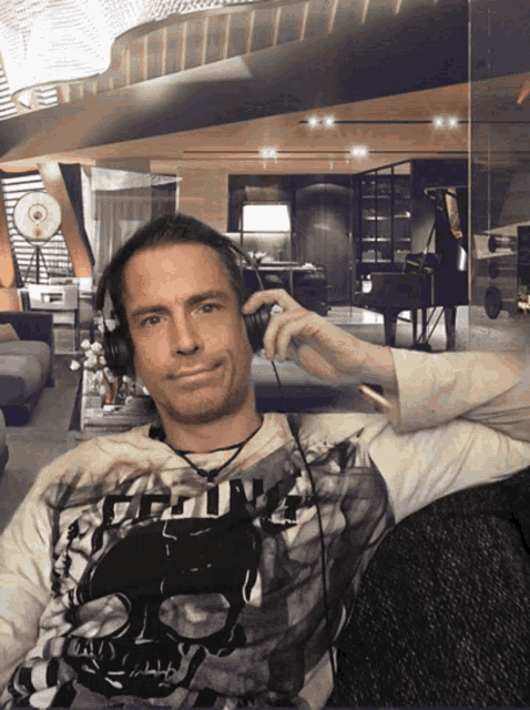 a man wearing headphones is wearing a shirt with a skull on the front