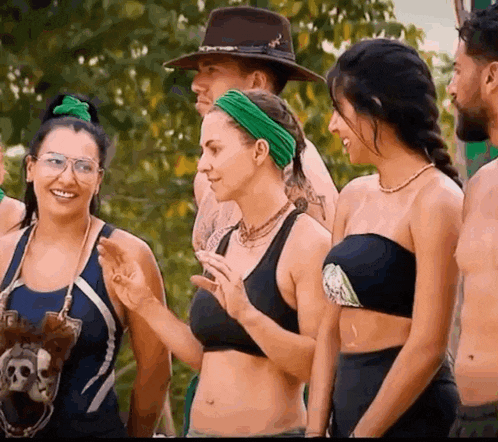 a group of people are standing next to each other and one woman is wearing a green headband