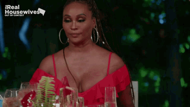 a woman in a red dress is sitting at a table with a sign that says real housewives out of context