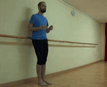 a man in a blue shirt and black pants is standing in front of a wall