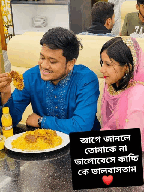 a man and woman sit at a table with a plate of food