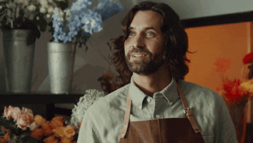 a man with long hair and a beard wears an apron
