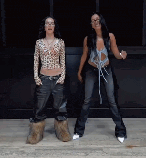 two women are standing next to each other and dancing in front of a building .