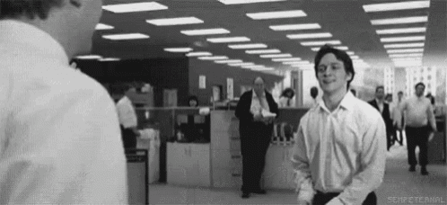 a black and white photo of two men standing in an office
