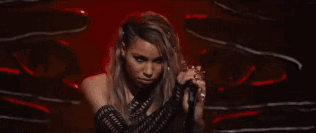 a woman in a black dress is holding a microphone and making a funny face .