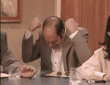 a man in a suit is sitting at a table with glasses of water and a pen .