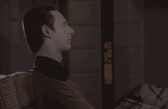 a man in a suit is clapping his hands in front of a sign that says ' emergency exit '