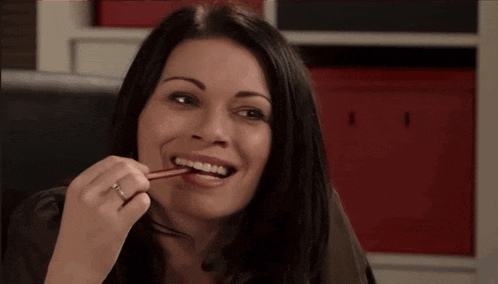 a woman with a ring on her finger is holding a pencil between her teeth