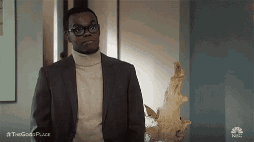 a man in a suit and turtleneck is holding a statue of a fish .