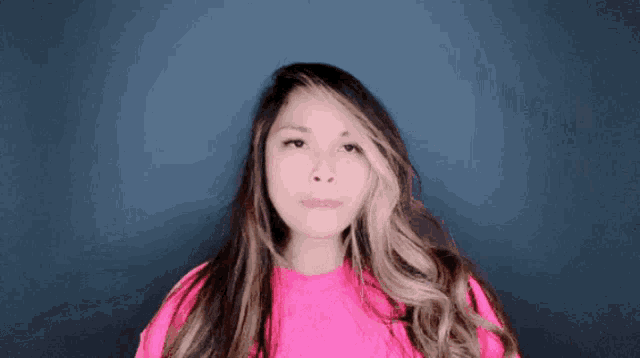 a woman with long hair wearing a pink sweater