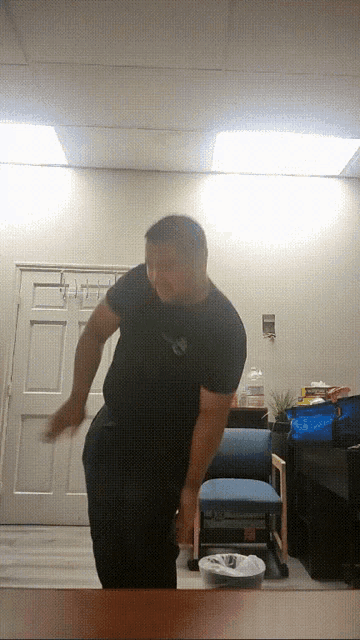 a man in a black shirt is standing in front of a chair