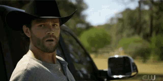 a man wearing a cowboy hat is sitting in a car with a cw logo on the side