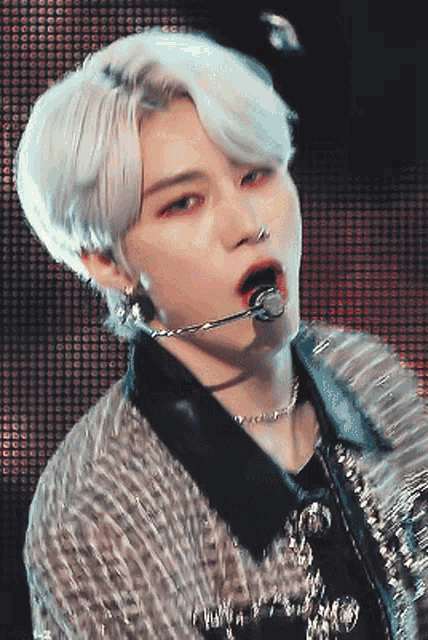 a close up of a person 's face with a microphone in his mouth
