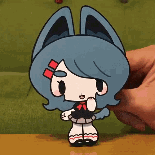 a person is holding a cartoon character with blue hair and ears